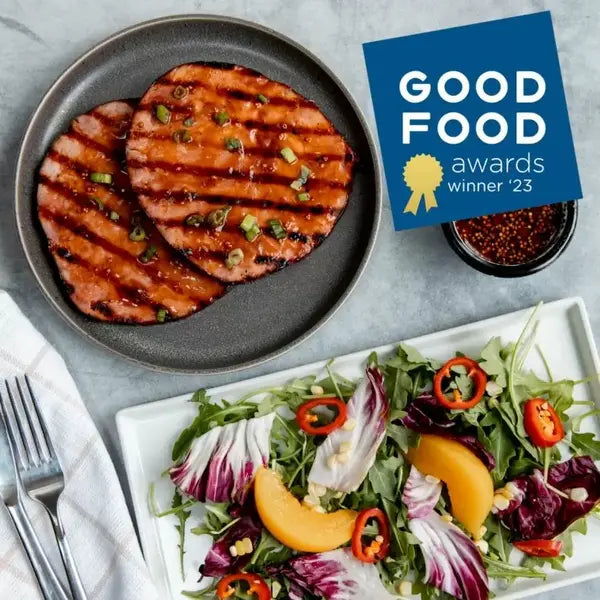 Grilled meat patties on a plate with a salad and 'Good Food Awards' winner badge.