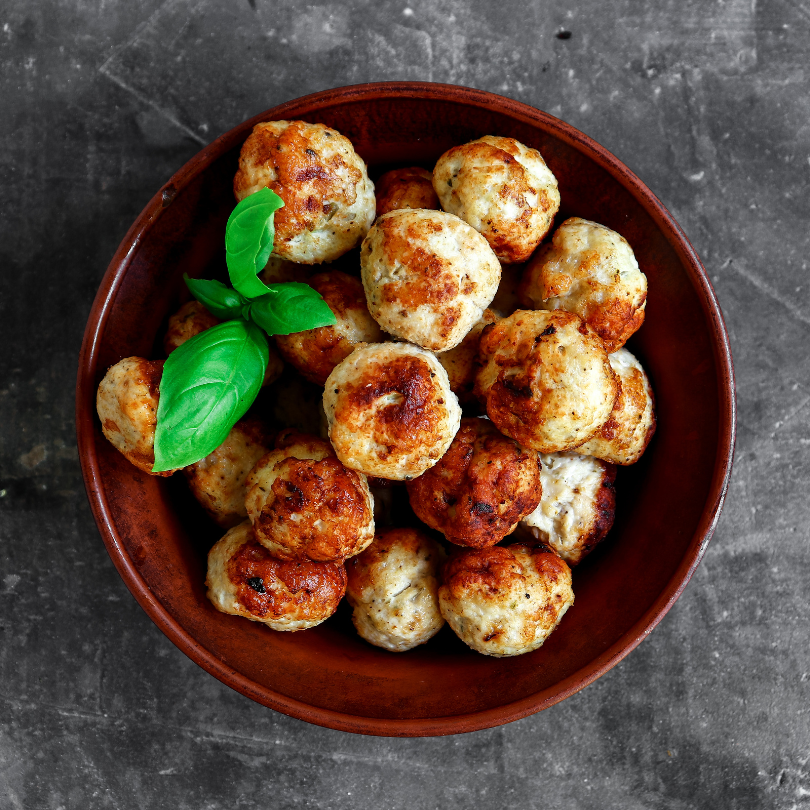 Brown bowl filled with chicken meatballs on a dark gray background