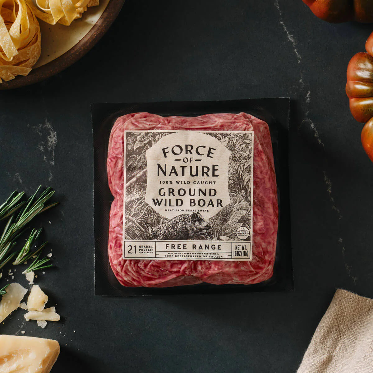 Packaged ground wild boar meat with 'Force of Nature' label on a dark surface.