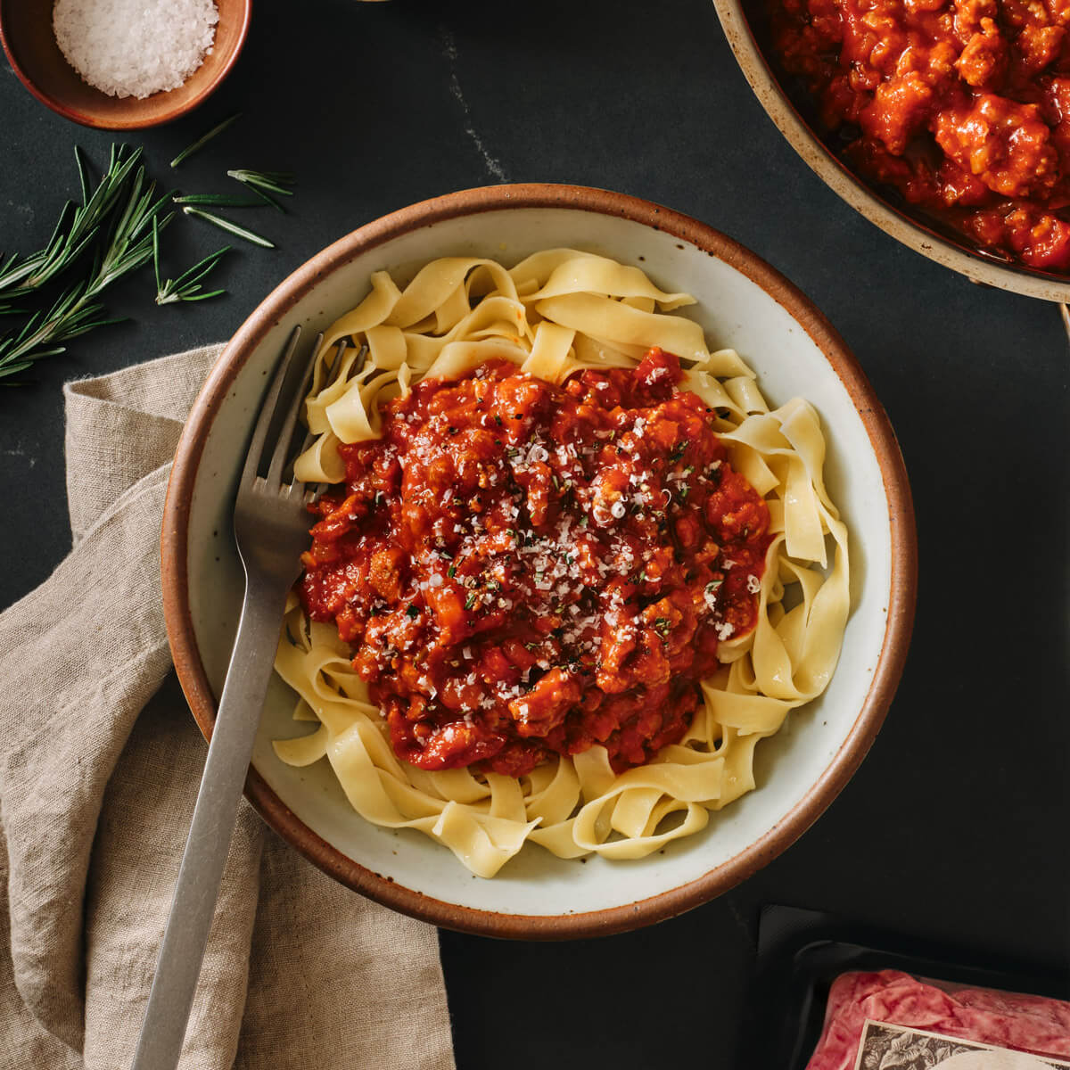 Pasta dish with red sauce in a bowl on a dark surface