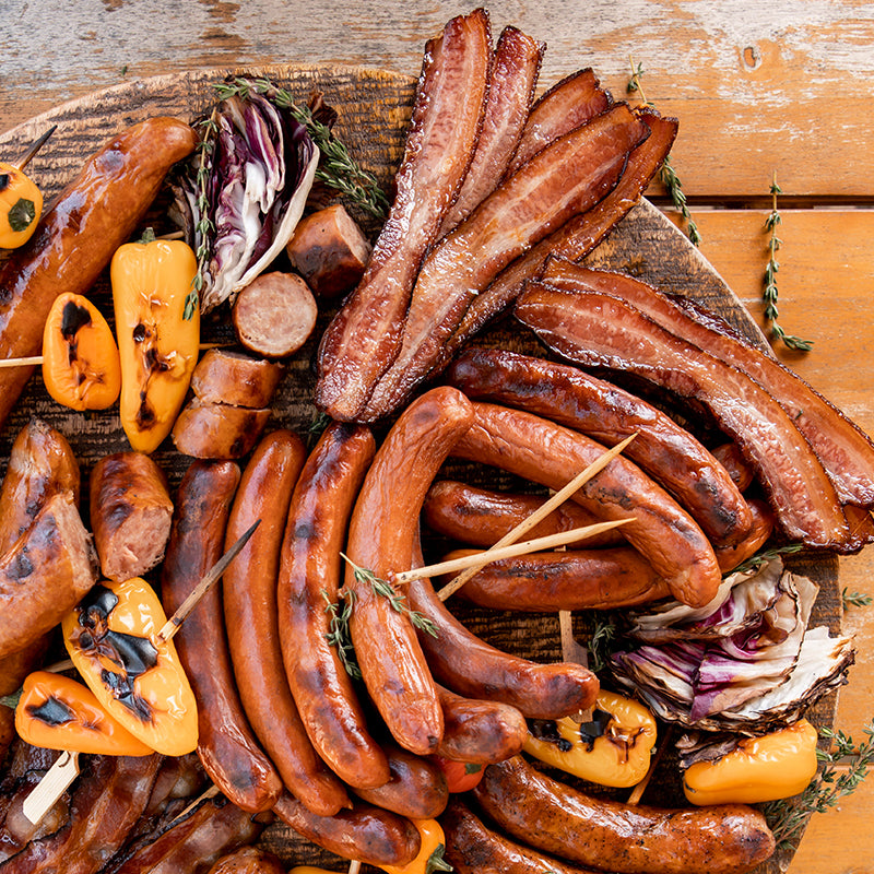 Assorted sausages and vegetables on a wooden board