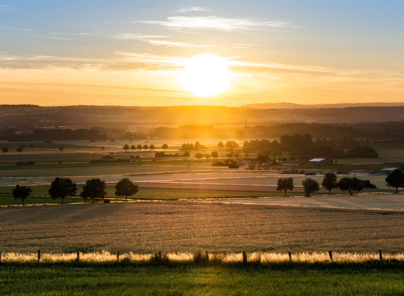 Sunset over a rural landscape with fields and trees