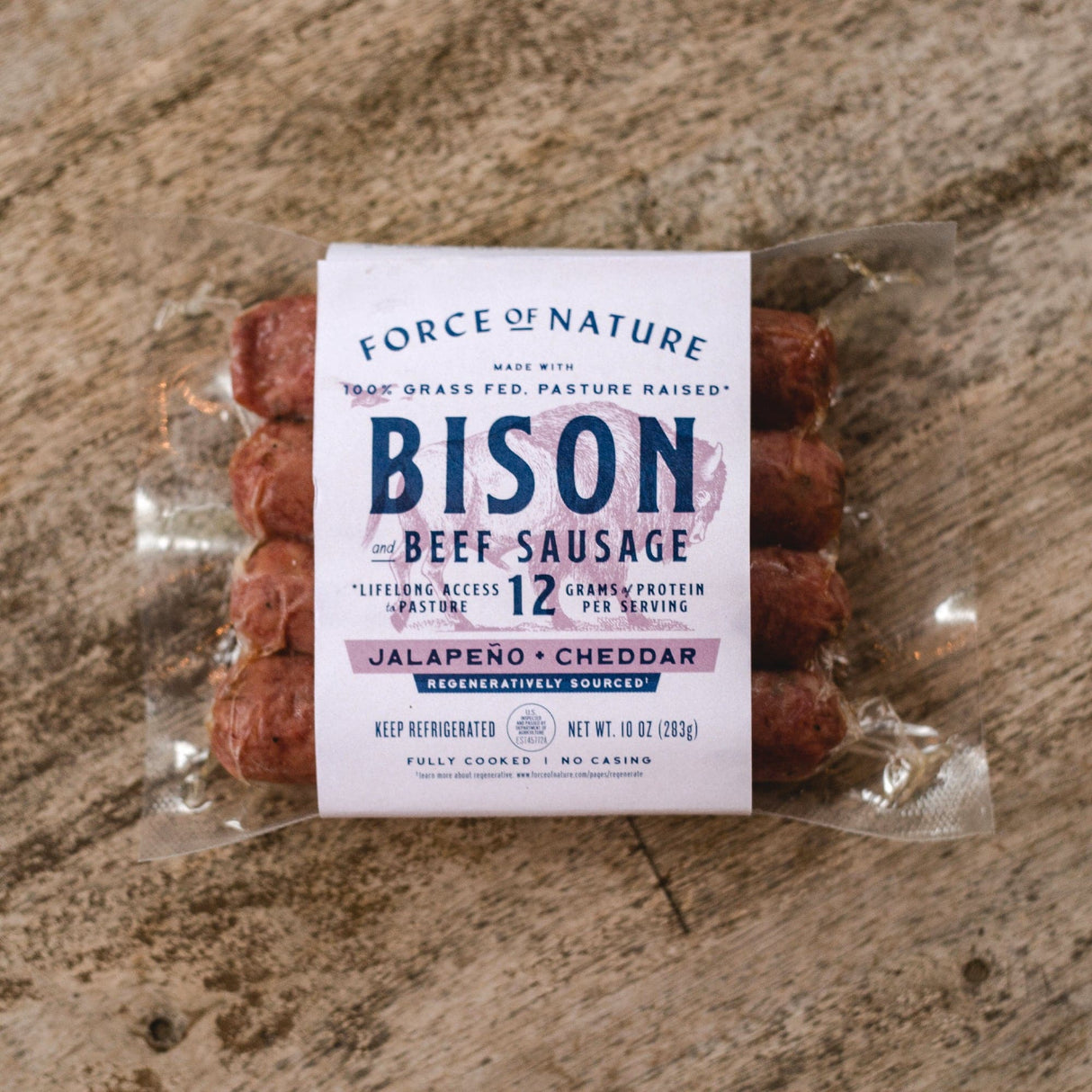 Packaged bison beef sausage with a label on a stone surface