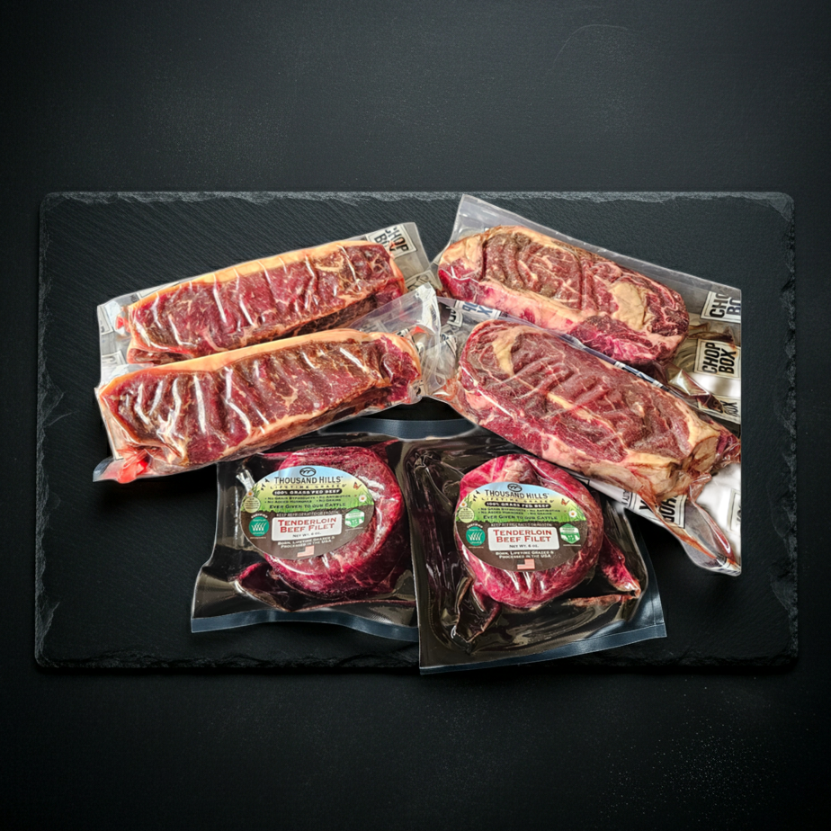 Packaged raw steaks on a dark slate surface