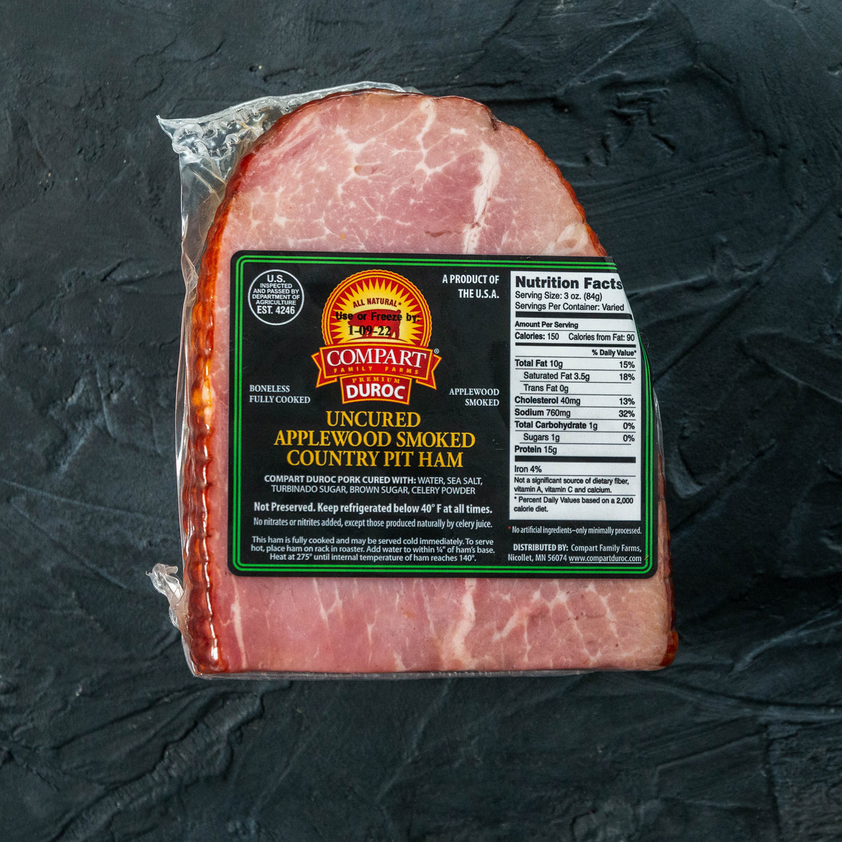 Packaged cooked ham with Compart Duroc label on a dark surface