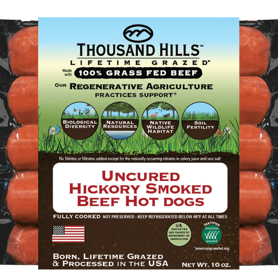 Package of Thousand Hills Uncured Hickory Smoked Beef Hot Dogs with branding and product details.