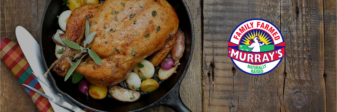 Roasted chicken with vegetables in a skillet on a wooden surface, featuring Murray's Family Farmed logo.