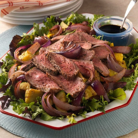 Grilled NY strip steak sliced over a summer squash and onion salad with balsamic glaze