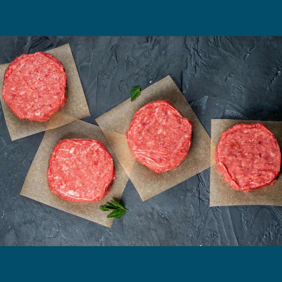 four 3 ounce raw beef sliders each on a square of butcher paper on a slate cutting board