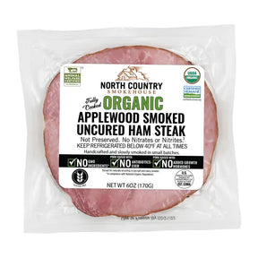 Packaged organic applewood smoked uncured ham steak with North Country Smokehouse label on a white background