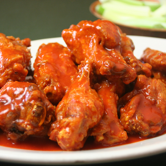 Party chicken wings slathered in buffalo sauce on a white plate