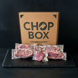 Chop Box packaging with raw meat packages on a black surface