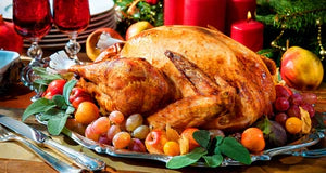Roasted turkey on a platter with fruits and candles on a festive table.