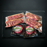Packaged raw steaks on a dark slate surface