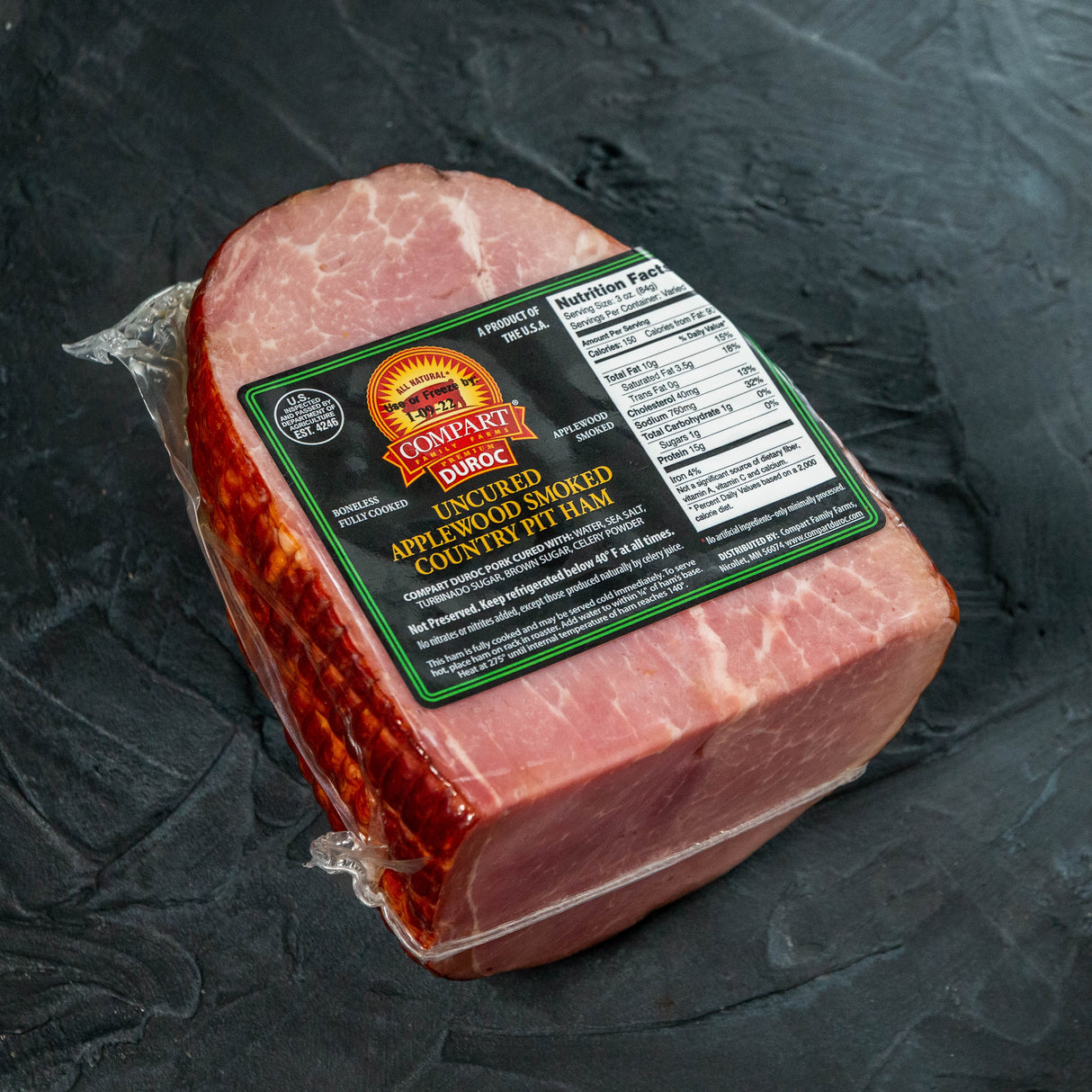 Packaged ham with a label on a dark surface