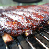 Barbecued ribs on a grill with a blurred background